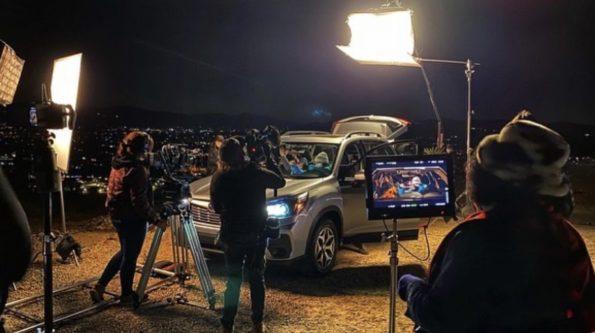 An image of a film set with lights, cameras, monitors all filming a car.
